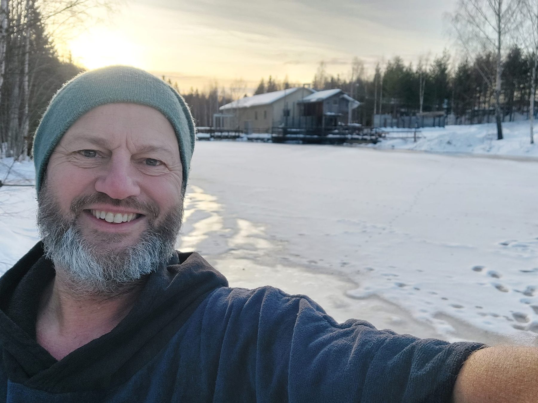 Erik van Tilburg op het bevroren meer, met de zon net boven de bomen