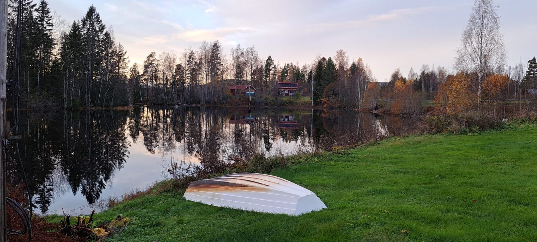 Roeiboot op de oever van het meer met herfstkleuren in de spiegeling
