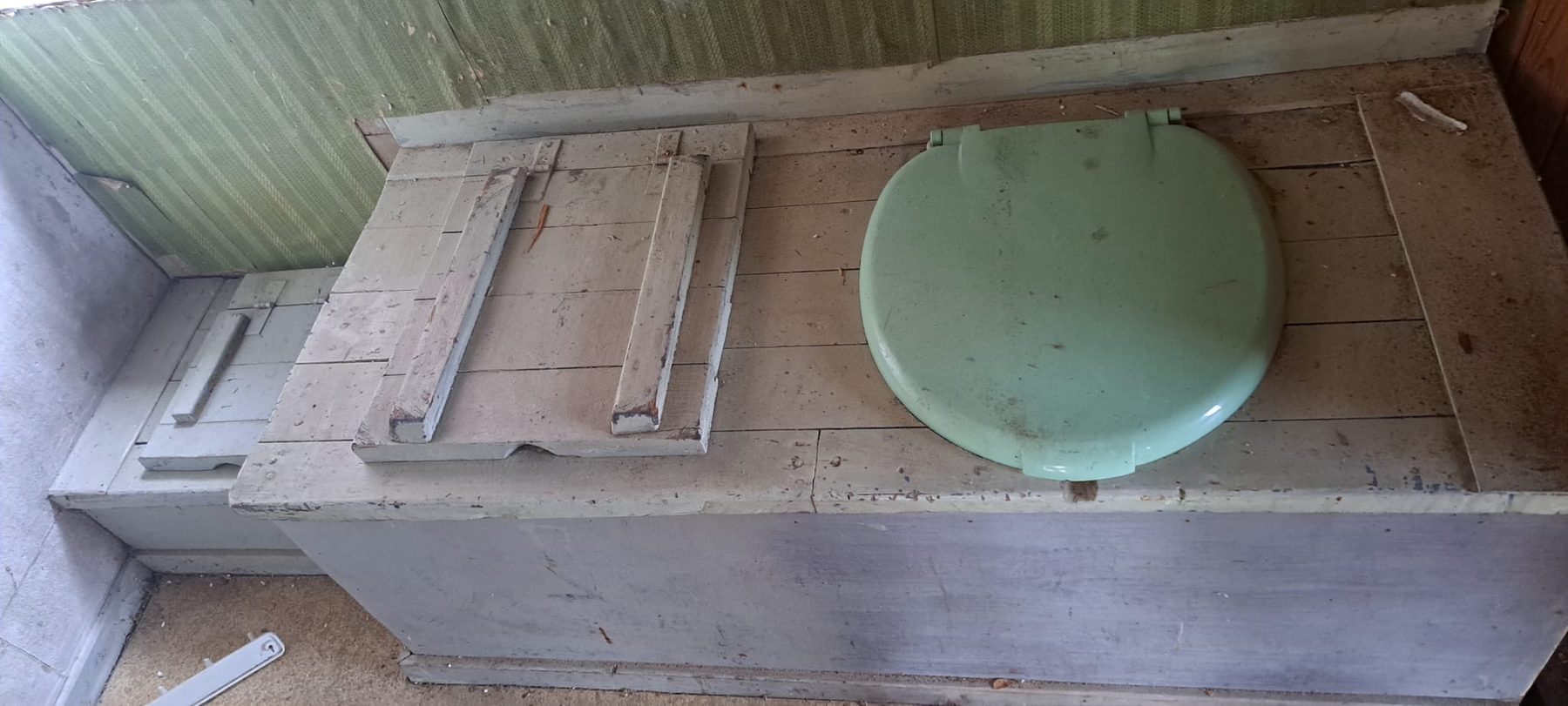 De oude houten toiletbank met groene bril in het bijgebouw